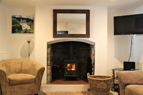 a living room with a fireplace and a mirror at Peacock Cottage in Cinderford