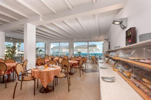 ein Esszimmer mit Tischen und Stühlen und Fenstern in der Unterkunft Hotel Riviera in San Vito lo Capo