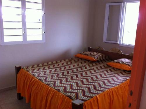 a bed in a bedroom with two windows at Haut de villa avec vue sur la mer in Sainte-Rose