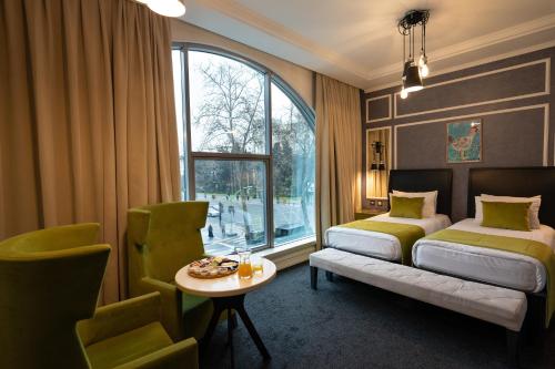 a bedroom with a bed and a table and a window at Dondar Hotel Formula 1 View in Baku