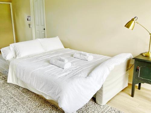 a white bed with two towels on top of it at Marigold Cottage, A Blue Mountains Oasis- Spacious, Views & Kangaroos in Little Hartley