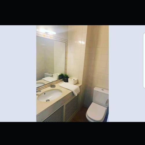 a bathroom with a sink and a toilet and a mirror at Aroeira Lisbon Golf & Beach in Charneca