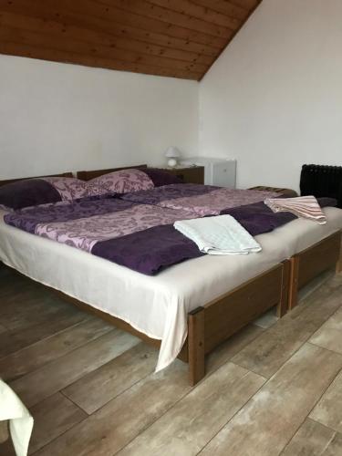 Cama grande en habitación con suelo de madera en Ilona Panzió, en Balatonlelle