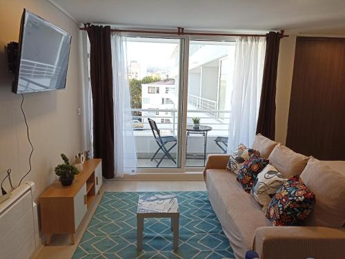 sala de estar con sofá, TV y balcón en Departamento full a pasos de la playa, en Viña del Mar