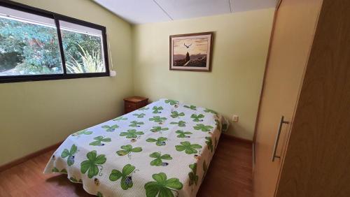 1 dormitorio con 1 cama con edredón verde y ventana en NATURALMENTE, en Santa Ana
