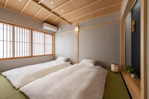 two beds in a room with a window at THE MACHIYA HOTEL TAKAYAMA in Takayama