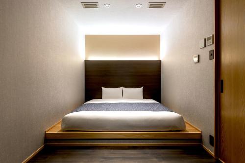 a bedroom with a bed with a wooden headboard at THE MACHIYA HOTEL TAKAYAMA in Takayama