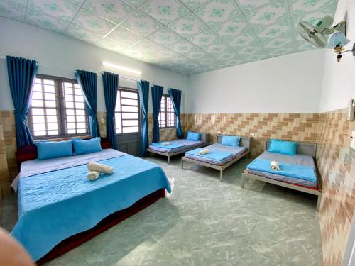 um quarto com 2 camas com lençóis azuis e janelas em Nam Cat Tien Homestay em Cat Tien