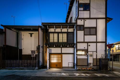 a white building with a brown door on a street at THE MACHIYA HOTEL TAKAYAMA in Takayama