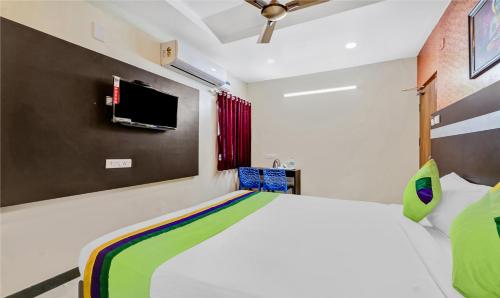 a bedroom with a bed and a tv on the wall at Treebo Sripadha Residency Alipiri Road in Tirupati