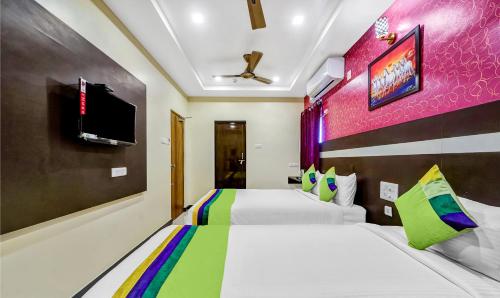 a bedroom with two beds and a tv on the wall at Treebo Sripadha Residency Alipiri Road in Tirupati