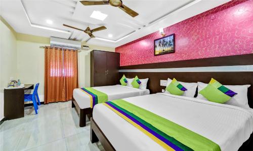 a bedroom with two beds and a pink wall at Treebo Sripadha Residency Alipiri Road in Tirupati
