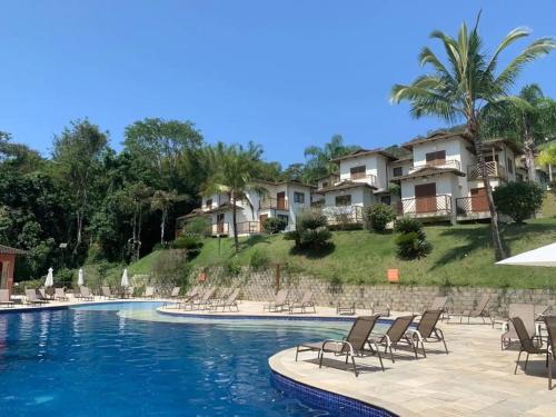 Residência em condom, 1 ou 2 suítes, vista para o mar, Praia do Curral, Ilhabela في إلهابيلا: مسبح في منتجع فيه كراسي وشقق