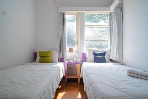 two beds in a room with a window at Urbanview Hotel FiFFa Kauman Malang in Malang