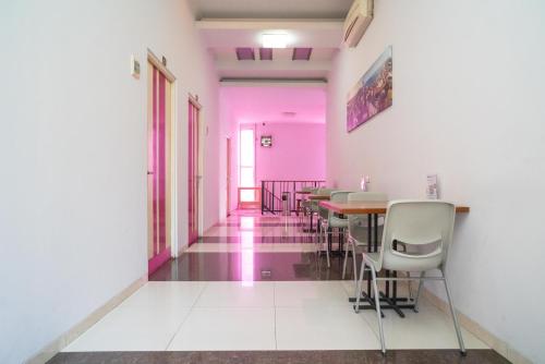 a dining room with pink walls and a table and chairs at Urbanview Hotel FiFFa Kauman Malang in Malang