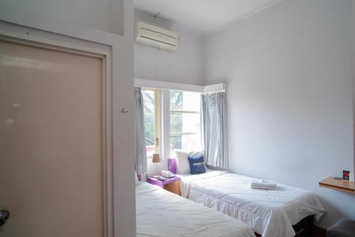 two beds in a room with a window at Urbanview Hotel FiFFa Kauman Malang in Malang