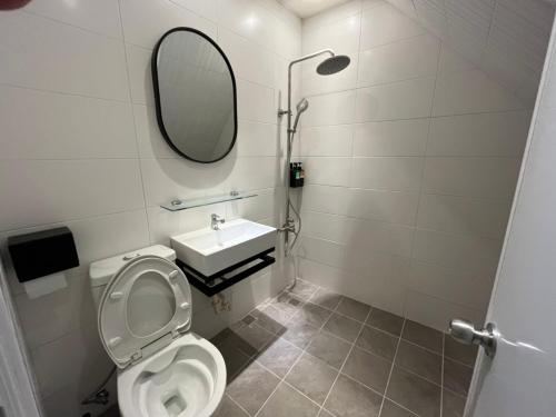 a bathroom with a toilet and a sink and a mirror at Rolling Pin Homestay in Tainan
