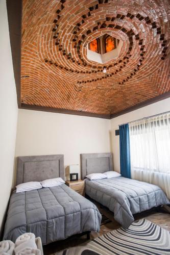 a bedroom with two beds and a brick wall at Real de Corralejo in San Miguel de Allende