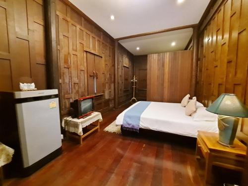 a bedroom with a bed and a tv in it at บ้านไทยรีสอร์ท in Ban Wang Kran