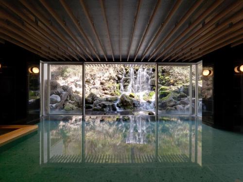 a glass house with a waterfall and a pool at Tateshina Grand Hotel Takinoyu in Chino