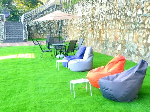 a group of chairs and tables on the grass at โรงแรม ชาโตว์วิสต้า in Chon Buri