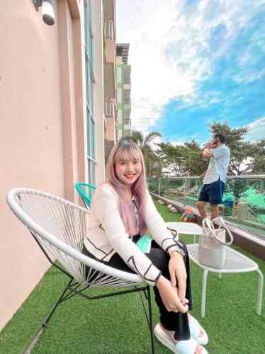 a woman sitting in a chair on a balcony at โรงแรม ชาโตว์วิสต้า in Chon Buri