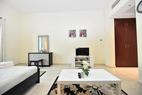 a living room with a bed and a table at Luxury Escapes - Budget Studio with Garden Views near Metro - MED64 DG in Dubai
