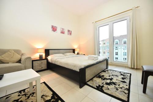 a bedroom with a bed and a couch and a window at Luxury Escapes - Budget Studio with Garden Views near Metro - MED64 DG in Dubai