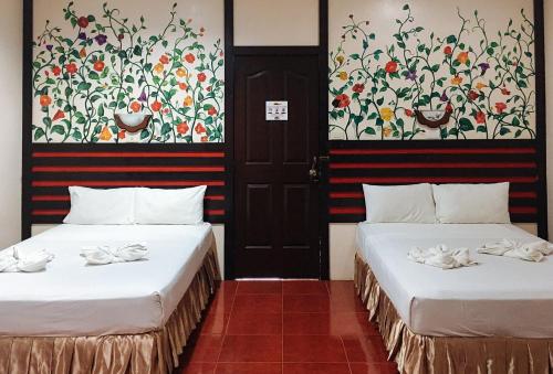 PanubiganにあるRedDoorz @ Mountain Citi Tourist Inn Canlaonの壁に絵画が飾られた部屋のベッド2台
