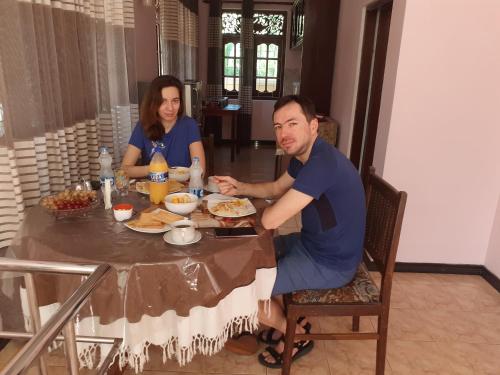 Um homem e uma mulher sentados à mesa a comer. em Villa184 em Ahungalla