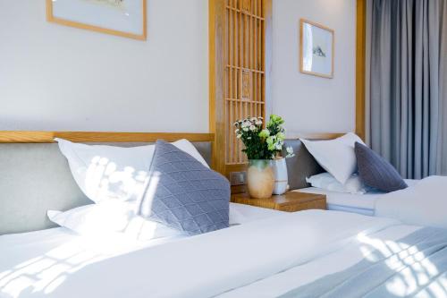 a bedroom with two white beds and a vase of flowers at Lijiang Gemmer Hotel in Lijiang