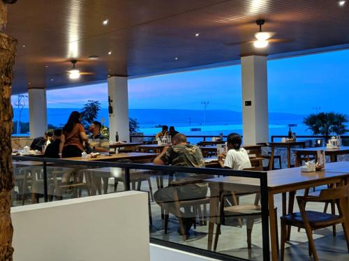 people sitting at tables in a restaurant with a view of the ocean at Kambaniru Beach Hotel and Resort in Waingapu