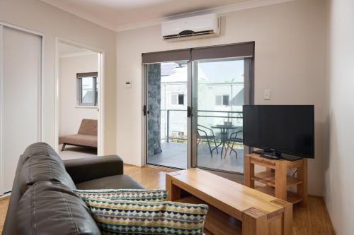 a living room with a couch and a flat screen tv at Airport Apartments by Vetroblu in Perth