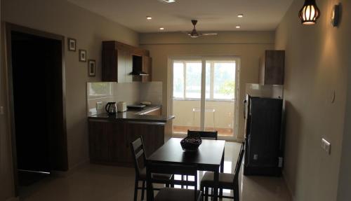 Una cocina con mesa y sillas y un refrigerador. en The Nest Holiday home, en Marmagao