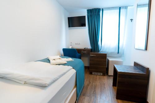 a room with two beds and a chair and a window at Hotel Myrsini in Kirchentellinsfurt
