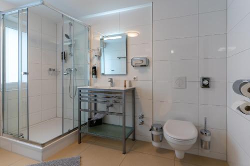 a bathroom with a shower and a toilet and a sink at Hotel Myrsini in Kirchentellinsfurt