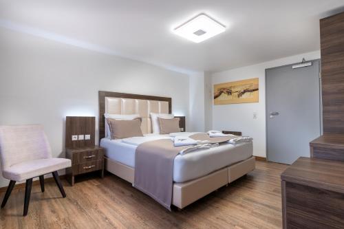 a bedroom with a large bed and a chair at Hotel Myrsini in Kirchentellinsfurt