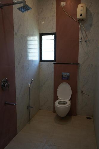 a bathroom with a toilet and a window at Sremethila Homestay in Marudhamalai