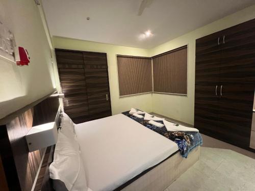 a bedroom with a white bed with wooden cabinets at Serenity 1BHK apartment, Alibag in Alibaug