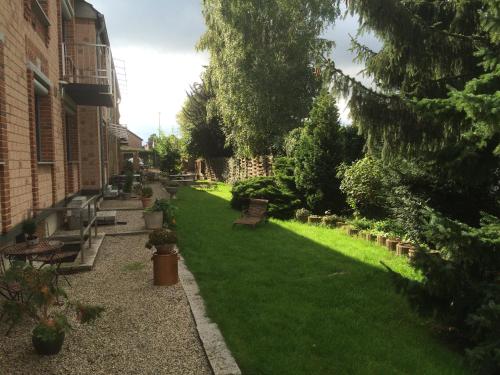 einen Garten mit Bänken, Bäumen und Gras in der Unterkunft Domizil Hotel Düren "Kastanienhof" in Düren - Eifel