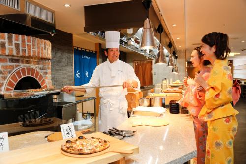 a man and woman in a kitchen preparing a pizza at Todaya in Toba