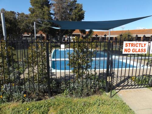 a fence with a no glass sign in front of a pool at Rivergum Motel in Echuca