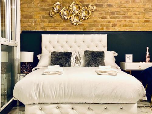 een slaapkamer met een groot wit bed met een bakstenen muur bij Duke and Duchess Apartments and Rooms - Private in Room Hot Tub Suites in Londen