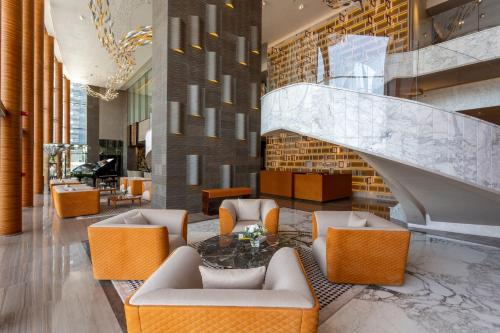 a lobby with chairs and a table and a staircase at The Bentley Luxury Hotel & Suites in Doha