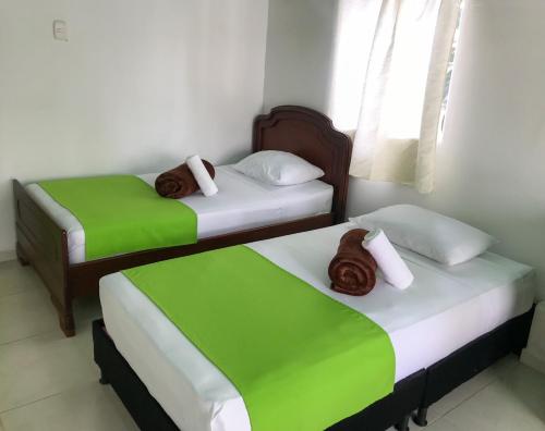 two beds in a room with green and white at Room in Guest room - Room with 1 double bed and 2 single beds Number 8 in Rizaralda