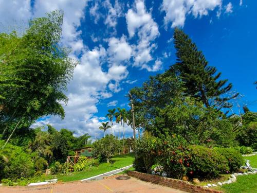 a park with trees and a blue sky with clouds at Room with 1 double bed and 2 single beds in Rizaralda
