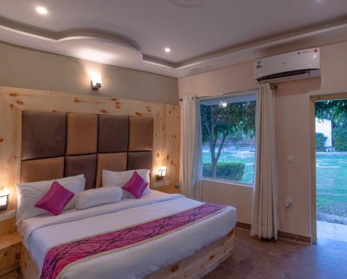 a bedroom with a large bed with a large window at The Tattwaa Corbett Spa & Retreat in Rāmnagar