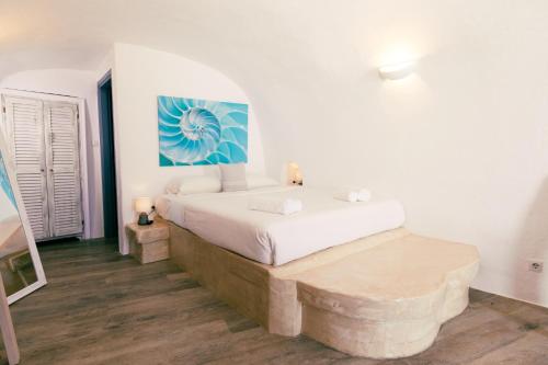 1 dormitorio con 1 cama y una pintura en la pared en Gemini Caves en Oia