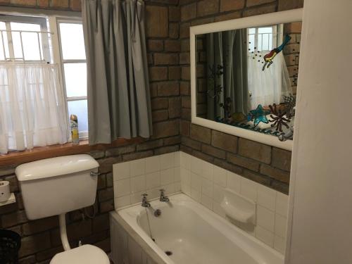 uma casa de banho com uma banheira, um WC e um espelho. em Storyhouse in Kommetjie em Kommetjie