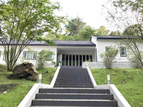 a white house with stairs in front of it at ゲストハウス　ペーパームーン in Yamanakako